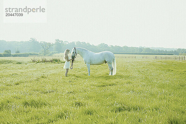 Young Woman Feeding Horse in Paddock