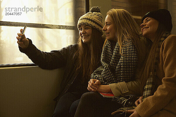 Teenage Girls Sitting on Train Taking Selfie