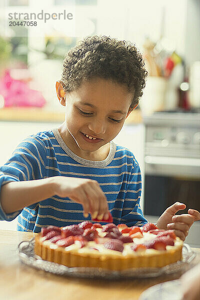 Boy Adding Strawberries to Cake