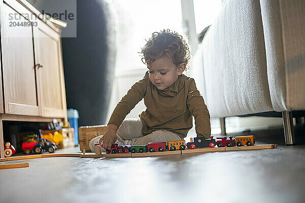 Toddler playing with a toy train on the floor.