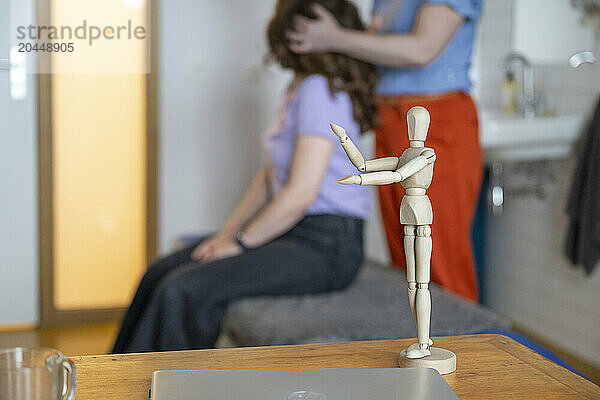 Wooden artist mannequin staged with hands together in a home setting.