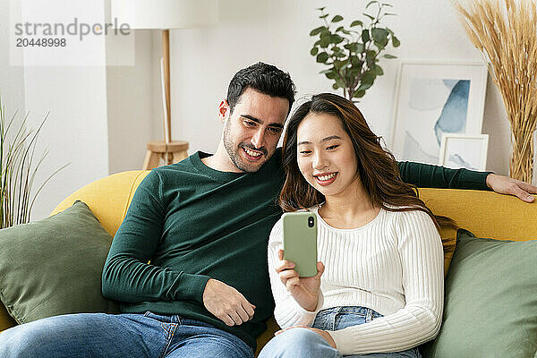 Couple looking at a smartphone on a couch.