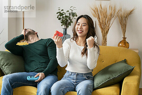 Man and woman enjoying a fun moment with video game controllers on a yellow sofa.