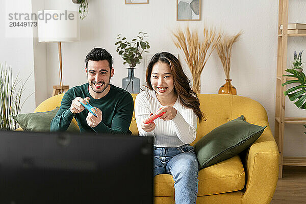 Two people playing video games on a couch.