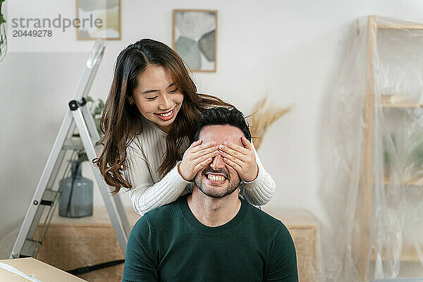 Woman covering man's eyes with her hands in a playful moment