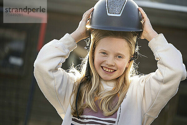 Smiling child holding a helmet outdoors.