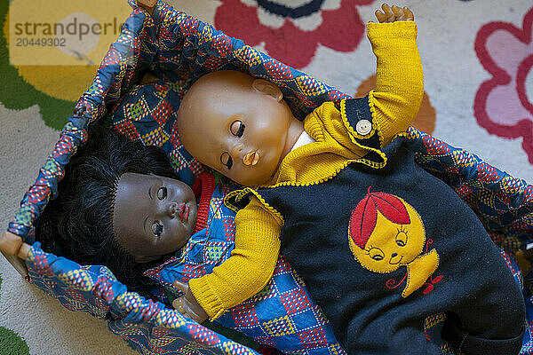 Two dolls lying in a child's playpen.