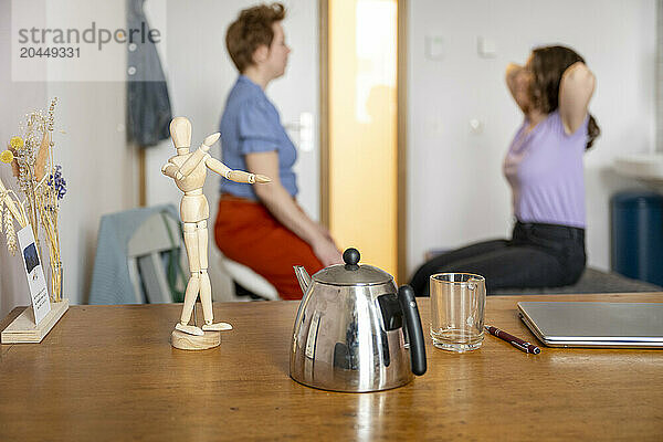 Wooden figure mimics a person stretching in a home office.