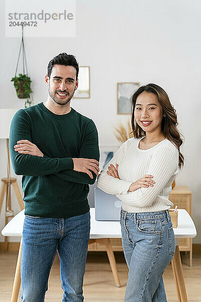 Two smiling adults standing confidently with arms crossed