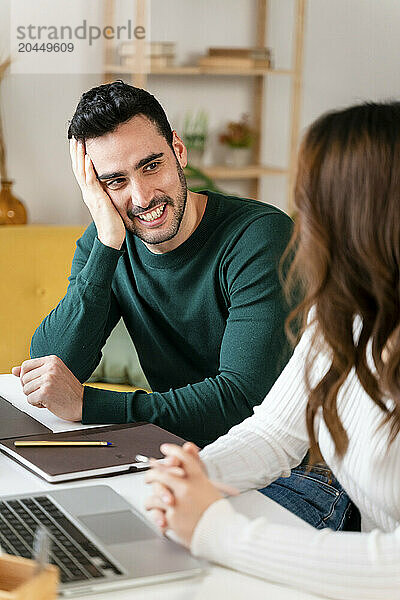 Man in green shirt smiling at woman near laptop