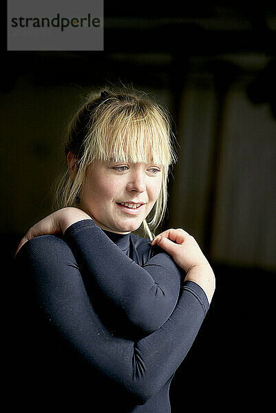 Smiling young woman with blonde hair wearing a dark top looking to the side.