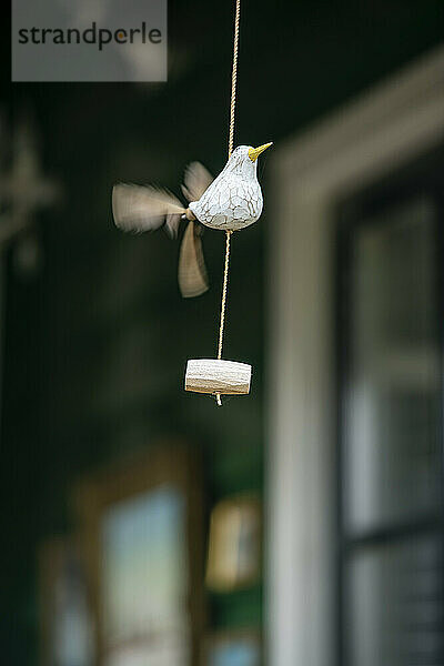 Ceramic bird figurine suspended on a string.