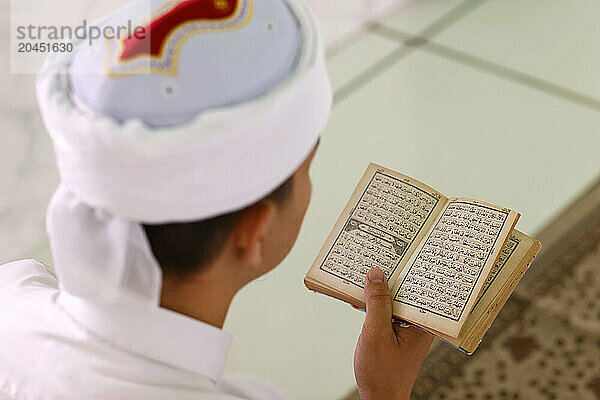 Muslim man reading an Arabic Holy Quran (Koran)  Jamiul Azhar Mosque  Vietnam  Indochina  Southeast Asia  Asia