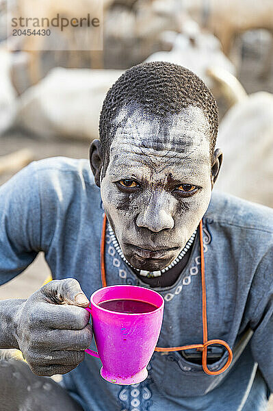 Dust covered man drinking local coffee  Mundari tribe  South Sudan  Africa