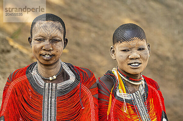 Mundari women in traditional dresses with facial scarring and ash on faces  posing on a rock  Mundari tribe  South Sudan  Africa