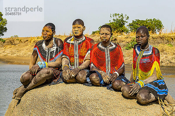 Mundari women in traditional dresses  with facial scarring and ash on faces  posing on a rock  Mundari tribe  South Sudan  Africa