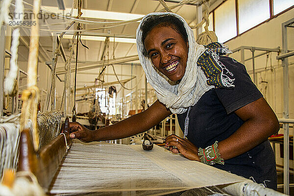 Friendly woman working on a hand weaving loom on a social project in the highlands of Eritrea  Africa