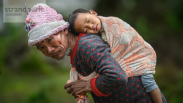 Nyishi Tribe  man carrying sleeping child on his back  Ziro Valley  Arunachal Pradesh  India  Asia