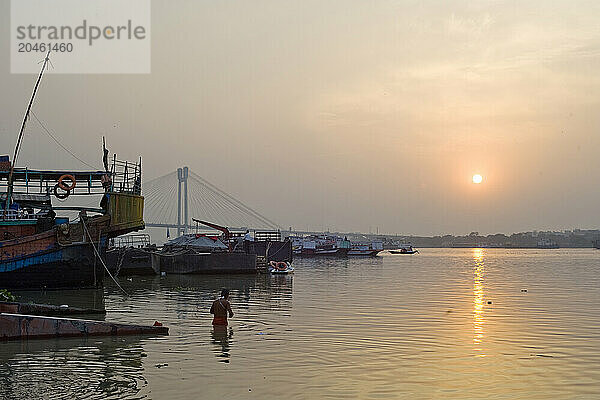 Bather and sunset over the Hooghly River with the Vidyesagar Setu Bridge in the background  Kolkata (Calcutta)  West Bengal  India  Asia