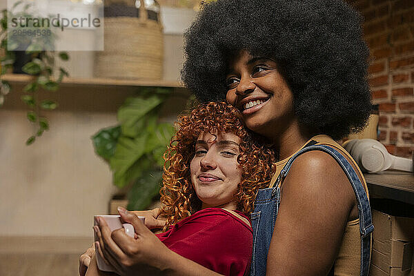 Redhead woman leaning on friend having coffee at home