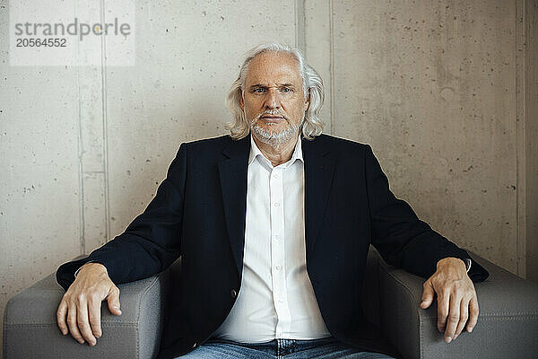 Confident senior businessman sitting on armchair at office