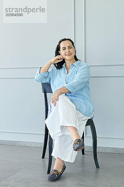 Smiling mature businesswoman sitting on chair at office