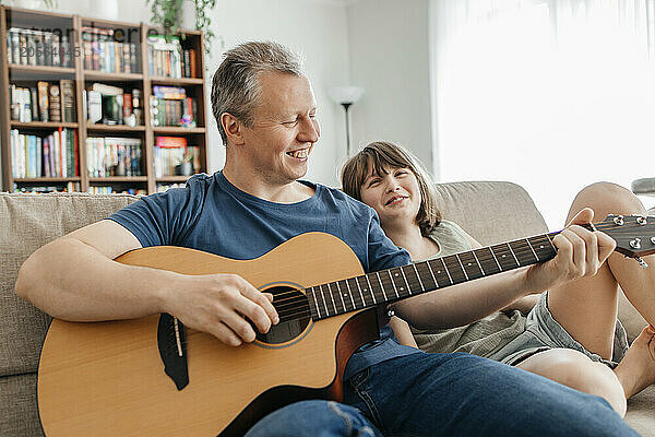 Father playing guitar with daughter at home