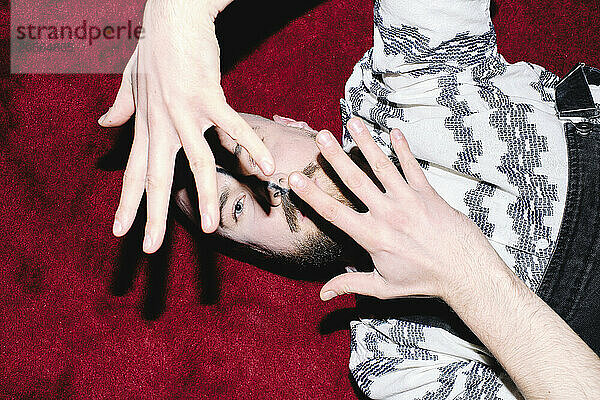 Man gesturing with hands and lying down on red carpet