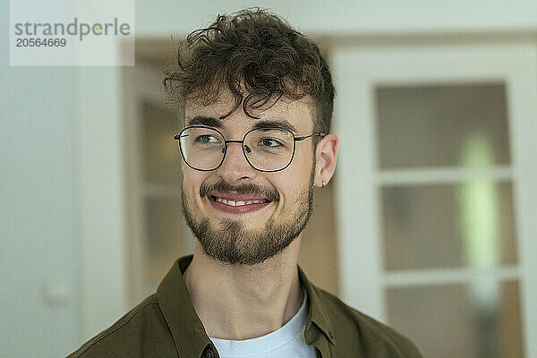 Smiling young handsome man wearing eyeglasses looking away at home