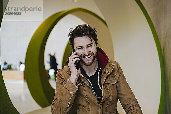 Happy man talking on smart phone in lobby