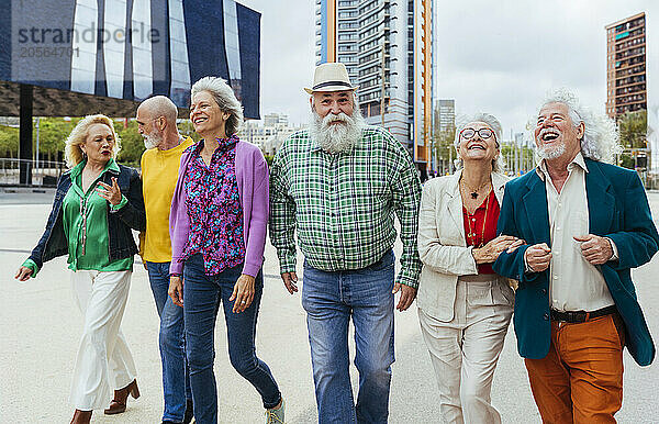 Carefree senior friends walking on street in city