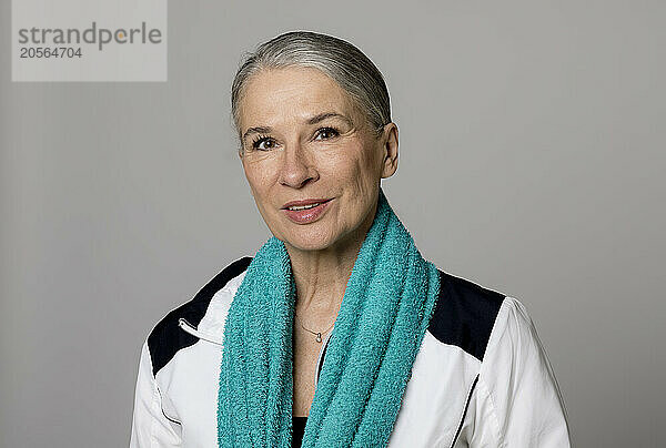 Smiling senior woman with turquoise towel against gray background