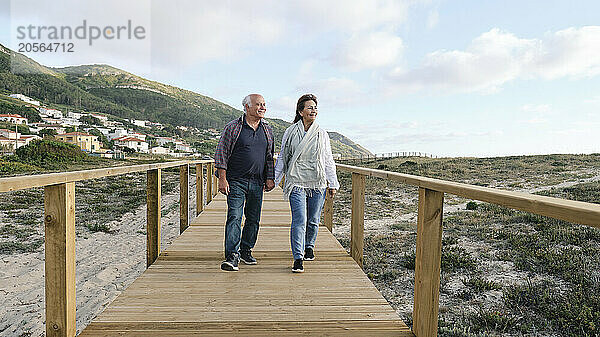 Smiling man and woman walking together on boardwalk