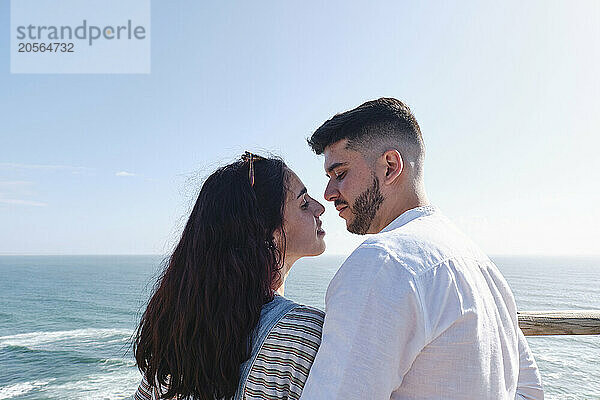 Romantic young couple with face to face in front of sky