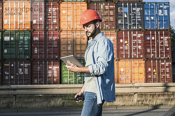 Foreperson using tablet PC in front of containers