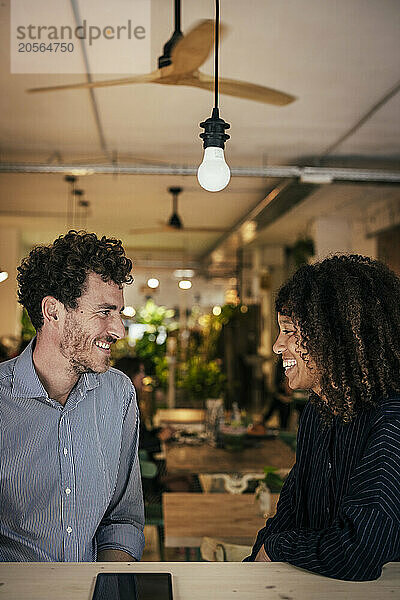 Smiling businessman sitting at cafe with coworker