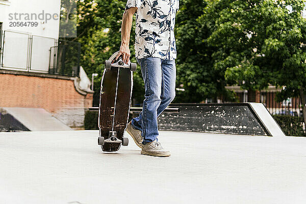 Man holding skateboard standing in park