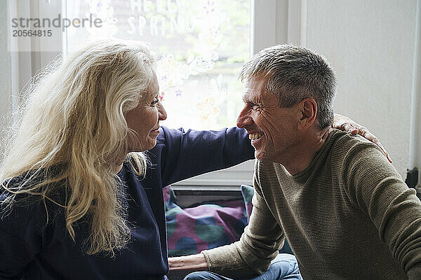 Happy retired senior couple looking face to face at home