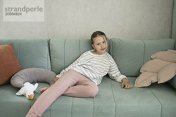 Smiling girl sitting on sofa at home