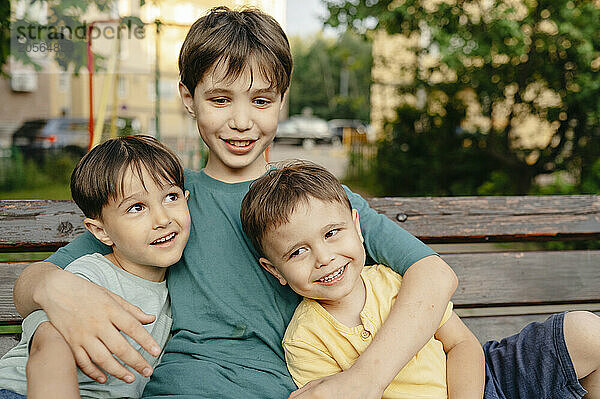 Happy siblings sitting on bench in playground