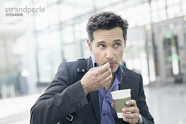 Mature businessman with disposable coffee cup at airport terminal