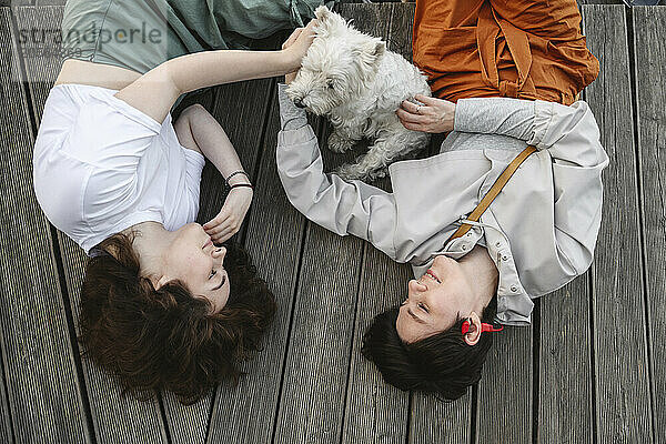 Mother and daughter with dog lying together on pier