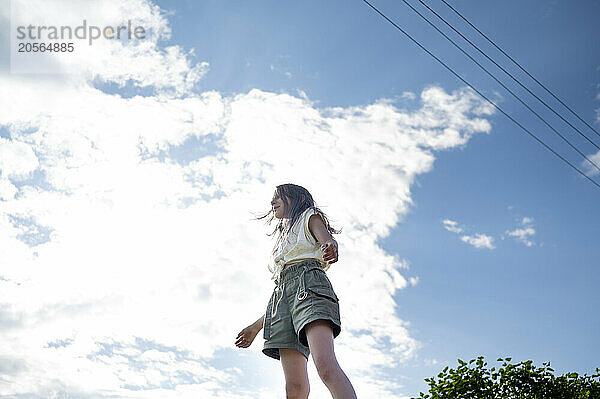 Girl standing under cloudy sky