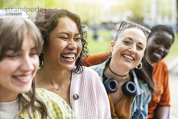 Cheerful female friends sitting together and laughing