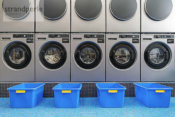 Blue baskets in front of washing machines at laundromat