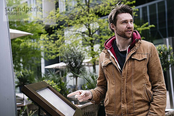 Man pointing at information board on street