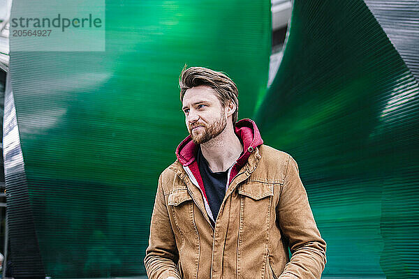 Handsome man posing in front of green wall