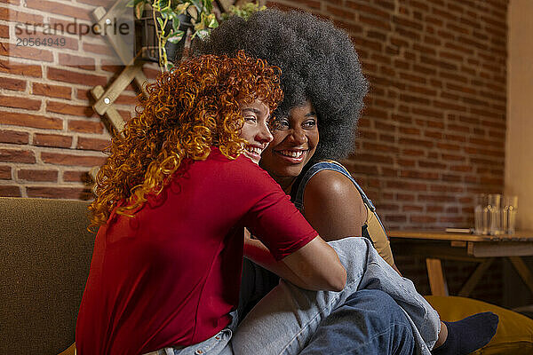 Happy curly hair woman sitting with roommate at home