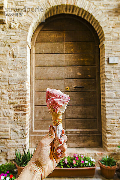 Woman hand holding gelato in front of old door