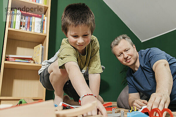 Father and son spending leisure time and playing with train toy at home